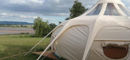 a white tent in a field next to a lake at Forest Glamping Retreat in Blakeney