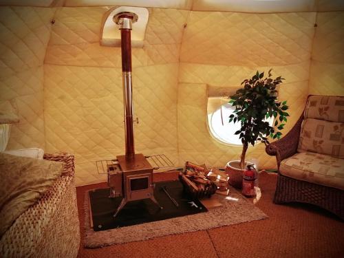 a living room with a stove in a tent at Forest Glamping Retreat in Blakeney