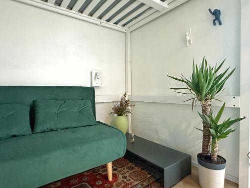 uma sala de estar com um sofá verde e vasos de plantas em Loft Biagio50 in Centro em Ferrara