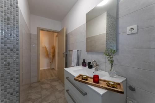 La salle de bains est pourvue d'un lavabo et d'un miroir. dans l'établissement Florami Apartment, à Kaštela