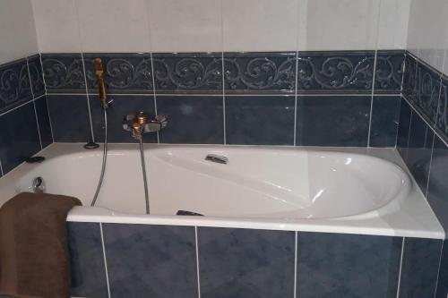 una vasca bianca in un bagno con piastrelle blu di LA CONFRERIE à MEURSAULT au CŒUR DE LA BOURGOGNE a Meursault