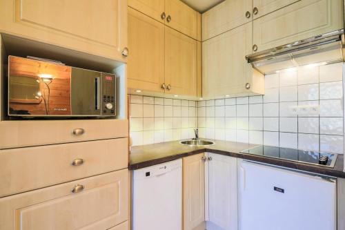 une cuisine avec des armoires blanches et un micro-ondes dans l'établissement Résidence Arbaron - maeva Home - Studio 4 personnes - Confort MAE-8638, à Flaine