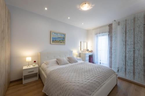 - une chambre blanche avec un grand lit et une fenêtre dans l'établissement Florami Apartment, à Kaštela