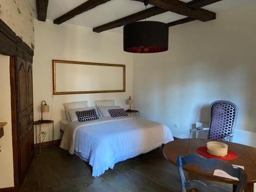 a bedroom with a white bed and a table at LA CONQUISE in Conques-en-Rouergue