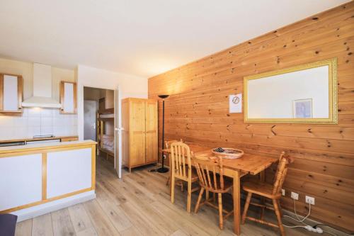 Il comprend une cuisine et une salle à manger avec un mur en bois. dans l'établissement Résidence Le Château de Crans - maeva Home - Studio 4 Personnes - Confort MAE-9176, à Flaine