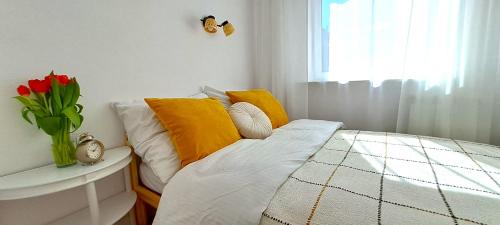 łóżko z żółtymi i białymi poduszkami i wazonem kwiatów w obiekcie Praska Syrena w Warszawie