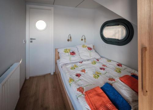 Un pequeño dormitorio con una cama con flores. en Hausboot Püntenel - stationär - Traumhafte Ferienwohnung AUF dem Wasser, en Kinrooi