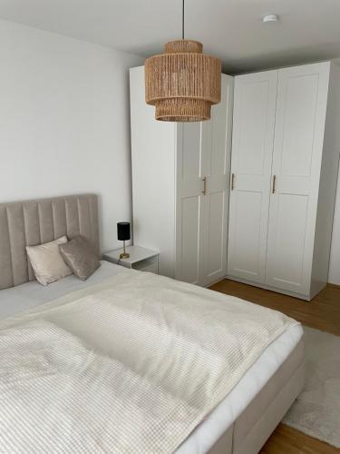 Un dormitorio con una gran cama blanca y una lámpara de araña. en Ferienwohnung mit Innenstadtanbindung en Múnich