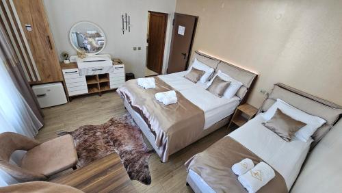a bedroom with two beds and a chair and a mirror at ЕЛЕГАНС къща за гости in Dospat