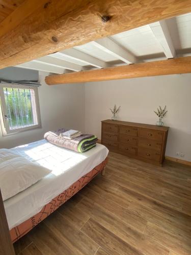 a bedroom with a bed and a window and wooden floors at Villa Quinson in Quinson
