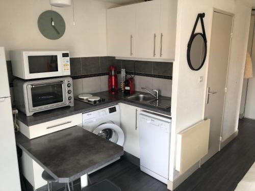 une petite cuisine avec un évier et un micro-ondes dans l'établissement Appartement Cap D’Agde, au Cap d'Agde