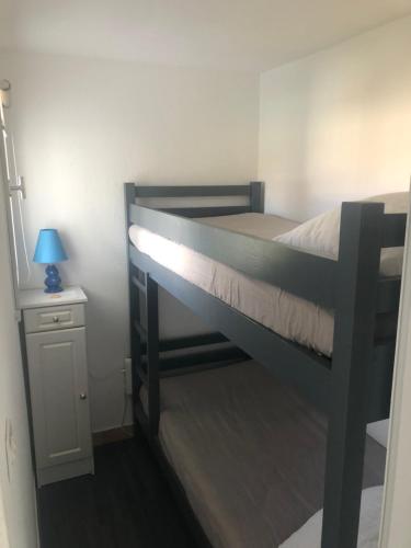 Ce lit superposé noir se trouve dans un dortoir doté d'une lampe. dans l'établissement Appartement Cap D’Agde, au Cap d'Agde