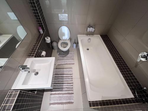 a bathroom with a tub and a toilet and a sink at Sky Cabins Apartments in Windhoek