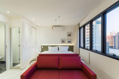 una camera con un letto e un divano rosso di BHomy Jardins Requinte e conforto CE1510 a San Paolo