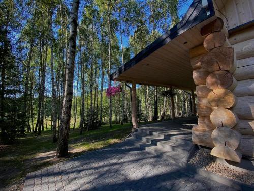 Cabaña de madera con porche y árboles al fondo en Leśne Klimaty, en Smolniki