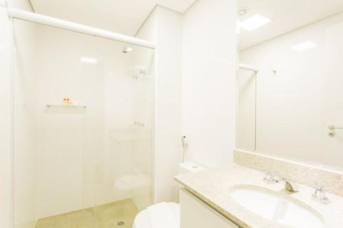 ein weißes Bad mit einem Waschbecken und einer Dusche in der Unterkunft BHomy Bela Vista Completo e localização APM1204 in São Paulo
