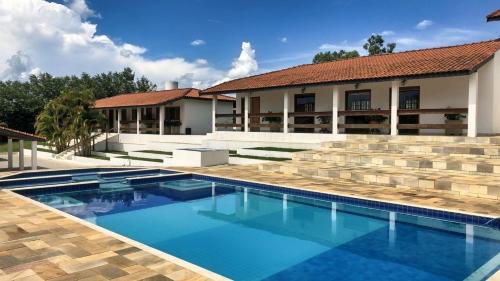 a swimming pool in front of a house at Sítio São Luiz: Experimente Autenticidade Rústica in Porangaba