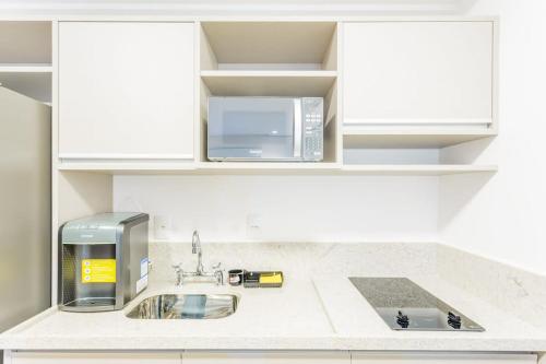 een witte keuken met een wastafel en een magnetron bij BHomy Bela Vista Conforto, AC e Lazer APM1202 in Sao Paulo