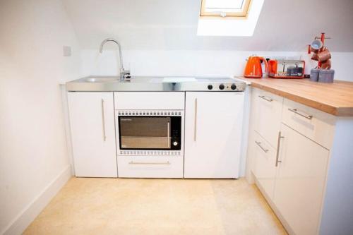uma cozinha com armários brancos e um lavatório em Doeling Barcombe em Isfield