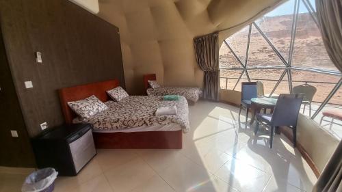 a bedroom with a bed and a table and a window at Sultan Luxury Camp in Wadi Rum