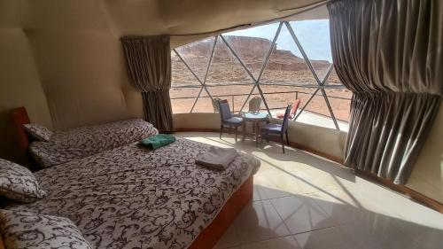 a bedroom with a bed and a view of the desert at Sultan Luxury Camp in Wadi Rum