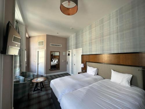 ダンファームリンにあるThe Guildhall and Linen Exchange Wetherspoonのベッド2台とテーブルが備わるホテルルームです。