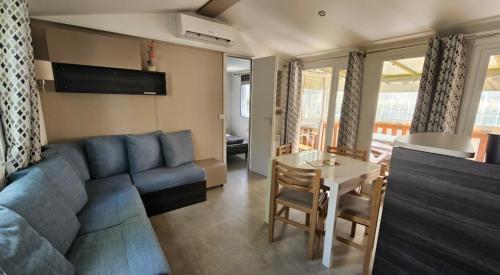 un salon avec un canapé bleu et une table dans l'établissement Grand mobil-home n°604 3ch tout confort au calme, à Gastes