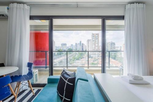 - un salon avec un canapé bleu et une grande fenêtre dans l'établissement BHomy Brooklin Moderno e com vista linda GB132B, à São Paulo