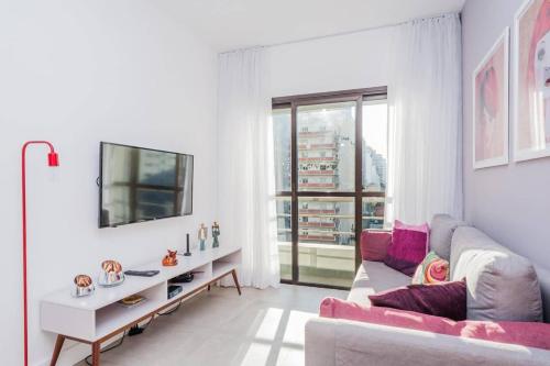 a white living room with a couch and a mirror at BHomy Madison in Sao Paulo