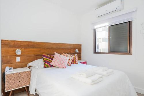 Schlafzimmer mit einem weißen Bett mit einem Kopfteil aus Holz in der Unterkunft BHomy Jardins Confortável e descolado MA606 in São Paulo