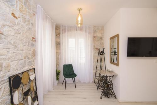 a living room with a television and a green chair at Sobe Bartul Trogir in Trogir