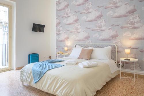 a bedroom with a white bed with clouds on the wall at Casa Risìu in Ragusa