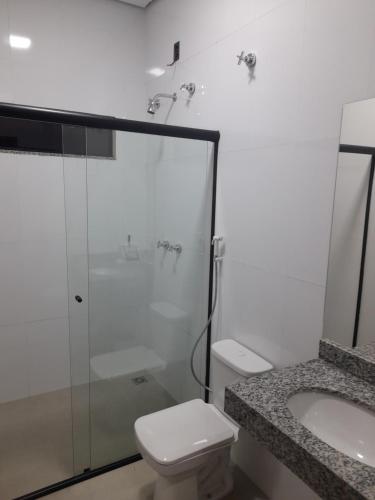 a bathroom with a shower and a toilet and a sink at Hotel Pimenta in Pimenta Bueno