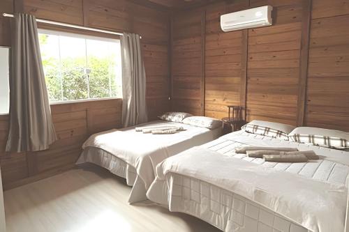 twee bedden in een kamer met houten wanden en een raam bij Rustic house - Prox Praia/BetoCarreiro in Penha