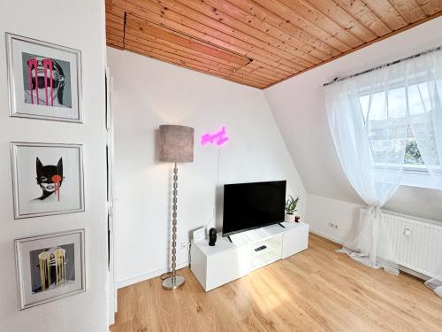 ein Wohnzimmer mit einem TV an einer weißen Wand in der Unterkunft ThinkPink! Apartment Ennepetal * Sehr modern * Top Lage in Ennepetal