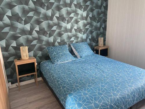 1 dormitorio con cama azul y pared geométrica en Maison de ville proche centre, en Pont-Audemer