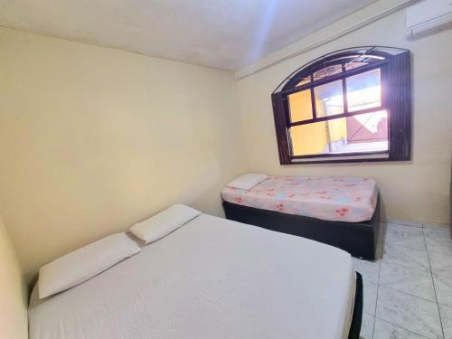 um pequeno quarto com 2 camas e uma janela em Casa Praia Grande - Arraial do Cabo em Arraial do Cabo