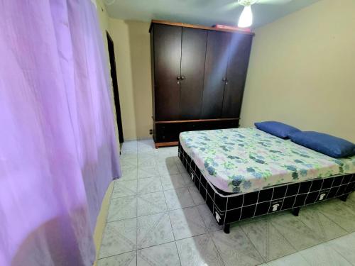 - une chambre avec un lit et une armoire en bois dans l'établissement Casa Praia Grande - Arraial do Cabo, à Arraial do Cabo