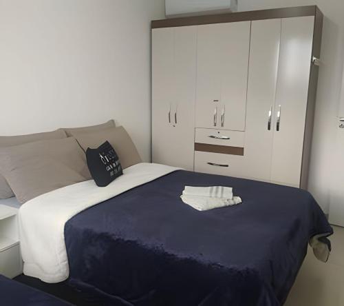 ein Schlafzimmer mit einem Bett mit einer blauen Decke und weißen Schränken in der Unterkunft Captiva Beach - 400m da PRAIA - WiFi - Netflix - Residencial Captiva in Navegantes