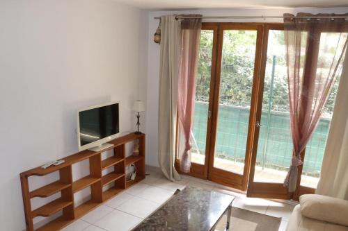 ein Wohnzimmer mit einem TV und einer Glasschiebetür in der Unterkunft Gionova furnished flat in Aix-en-Provence