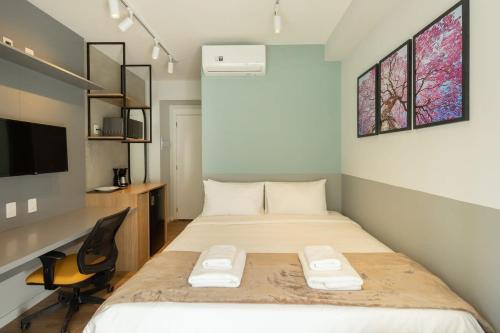 Schlafzimmer mit einem Bett, einem Schreibtisch und einem TV in der Unterkunft BHomy Brooklin - Charmoso com varanda BUR108 in São Paulo
