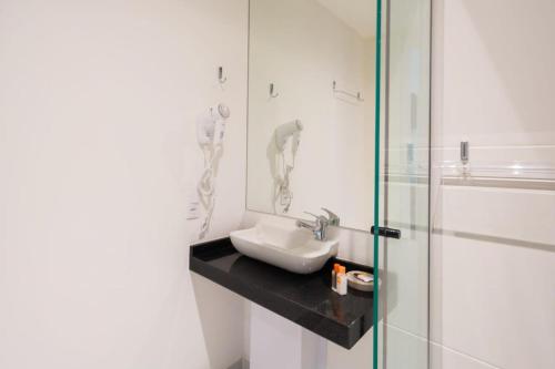 uma casa de banho com um lavatório e uma cabina de duche em vidro. em BHomy Brooklin - 300m estacão da Brooklin BUR101 em São Paulo