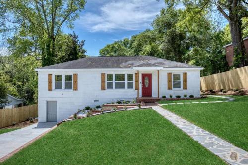 a white house with a red door and a yard at New! Comfy Home with Playground Near Ft Moore! in Columbus