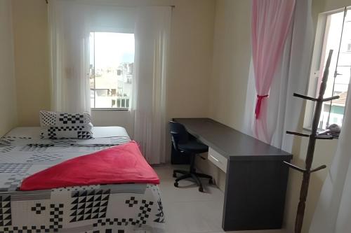 a bedroom with a desk and a bed with a red sheet at Apto a 300m da praia, próx. Aeroporto, BetoCarrero in Navegantes