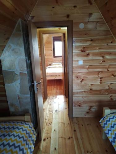 a room with wooden walls and a room with a bedroom at Brown cabin in Žabljak