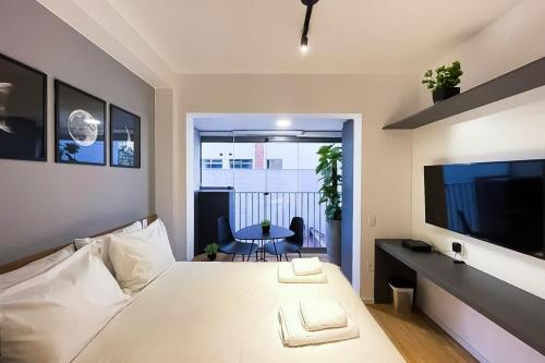 um quarto com uma grande cama branca e uma mesa em BHomy Brooklin - Novo c varanda integrada BUR102 em São Paulo