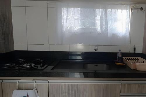 uma cozinha com um fogão, um lavatório e uma janela em Apto a 300m da praia, próx. Aeroporto, BetoCarrero em Navegantes