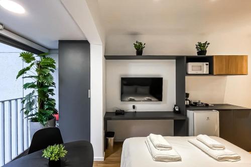 um quarto com uma cama e uma cozinha com uma televisão em BHomy Brooklin - Novo c varanda integrada BUR102 em São Paulo