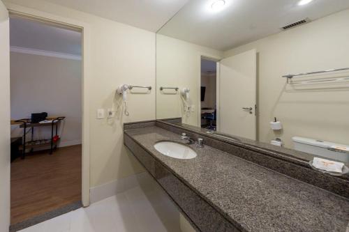uma casa de banho com um lavatório e um espelho grande em BHomy Campo Belo - Ao lado do aeroporto ATL1113 em São Paulo
