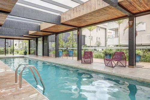 a swimming pool with two chairs in a building at BHomy Campeche Condomínio delicioso Spa club in Florianópolis